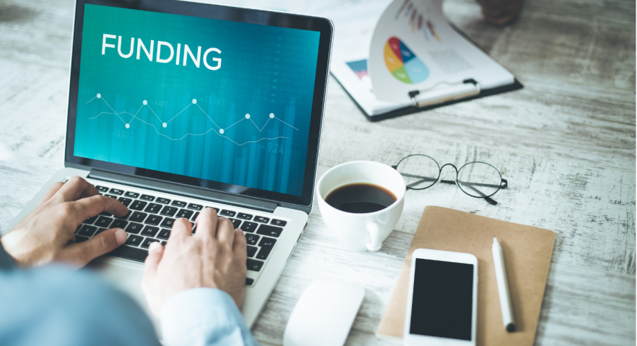 Händer och dator försedda med text Funding