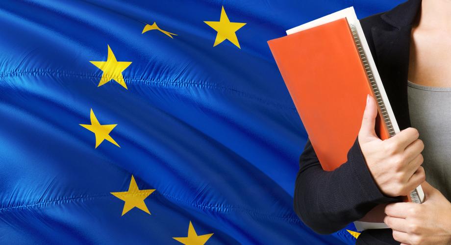 EU-lippu, jonka oikeassa laidassa näkyy naisen käsissään pitelemä kirja.