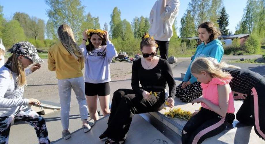 Joukko nuoria tekee seppeleitä ja kiipeilee.
