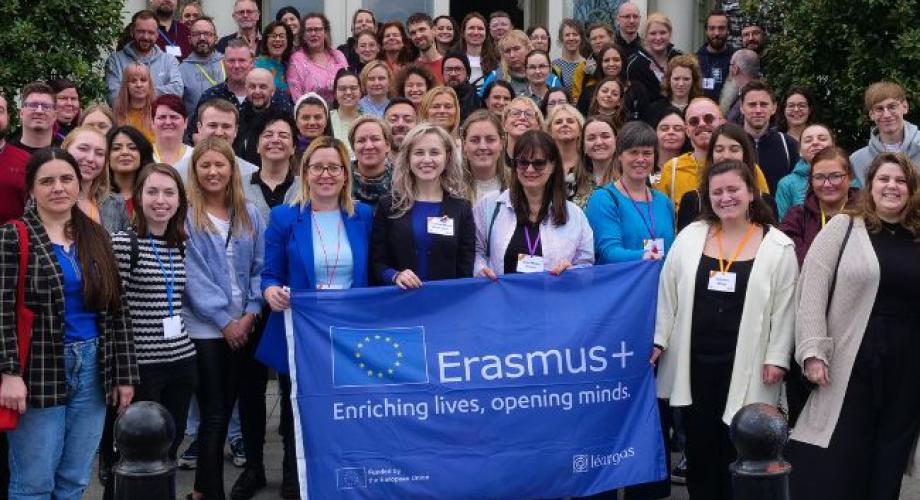 Suuri ihmisjoukko Erasmus+ -lipun taakse kokoontuneena.