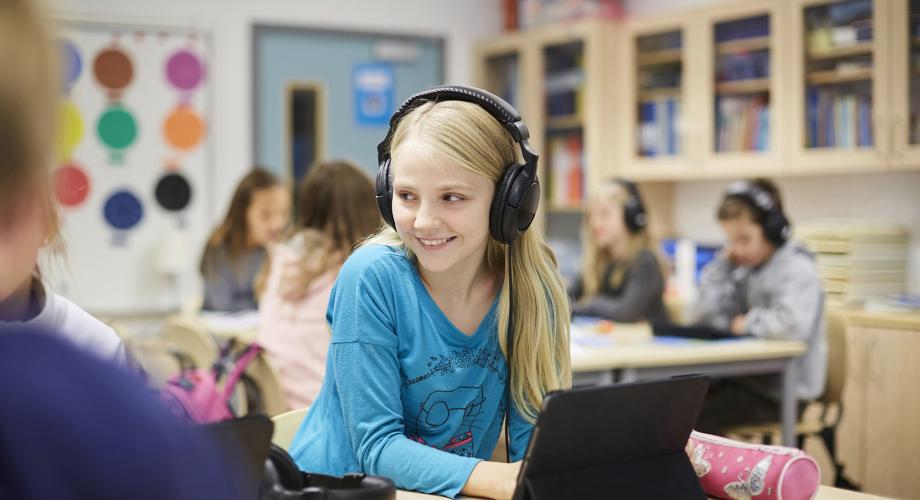 Vaaleahiuksinen lapsi hymyilee kuulokkeet korvillaan.