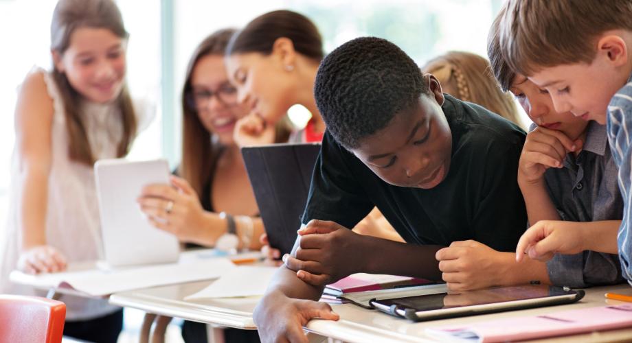 Oppilaita luokassa tutkimassa tabletteja