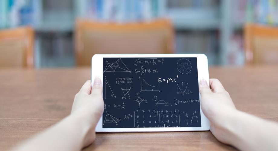  Händerna håller en tablet. Matematiska formler kan ses på tablet.