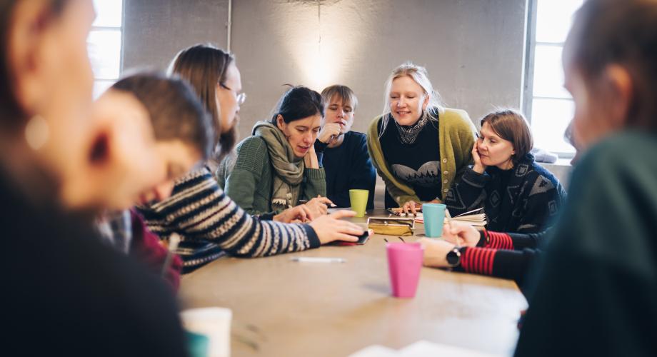Joukko nukketeatteriammattilaisia kokoontuneena keskusteluun pöydän äärelle.