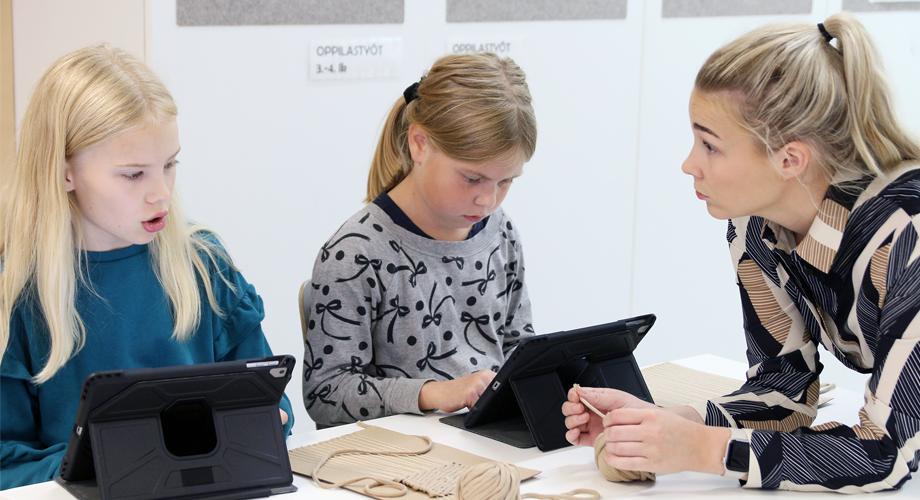 Opettaja ohjaa oppilaita, jotka työskentelevät tableteilla