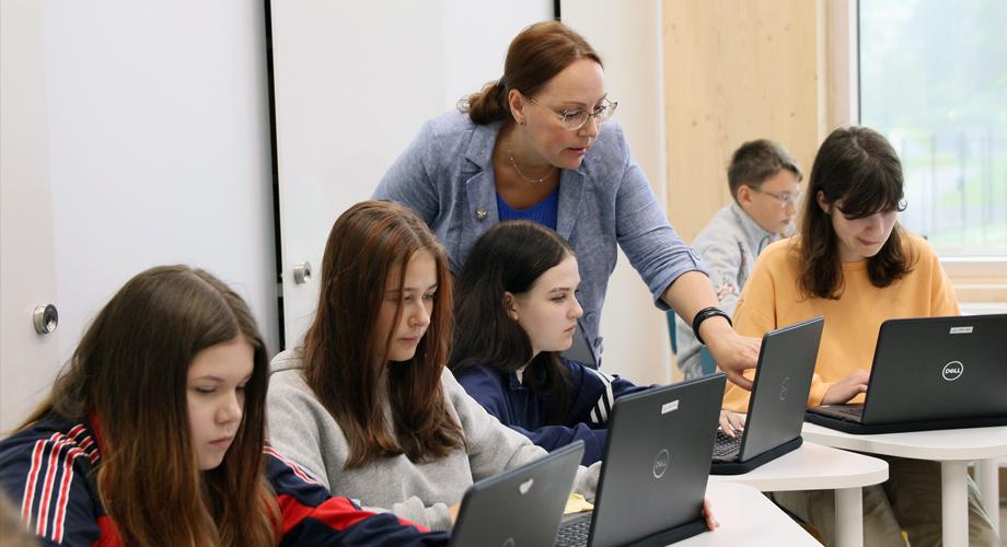 Opiskelijoita tietokoneella opettajan kanssa