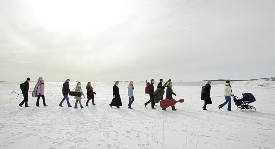 Ryhmä orkesterimuusikoita kävelee talvisella merenjäällä instrumenttilaukkuja kantaen.