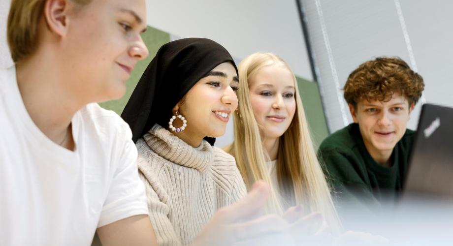 Neljä oppilasta kannettavan tietokoneen äärellä 