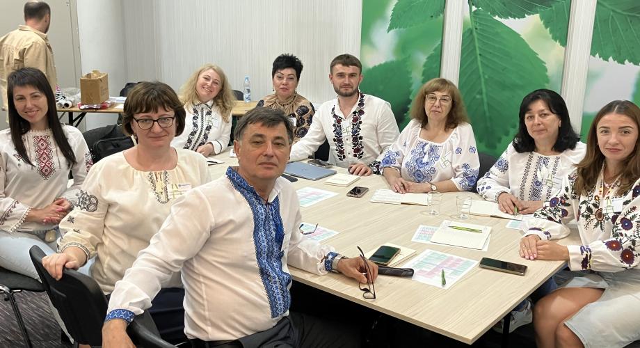 Ryhmä kansallispukuisia ukrainalaisia istuu neuvottelupöydän ympärillä