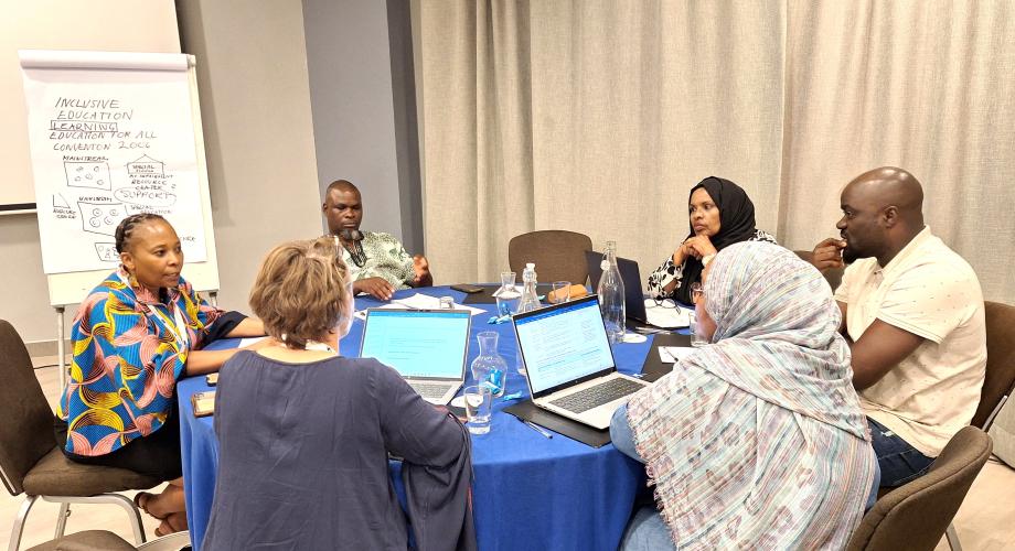 Six workshop participants are sitting together around a round table and working on a groupwork project in the workshop.