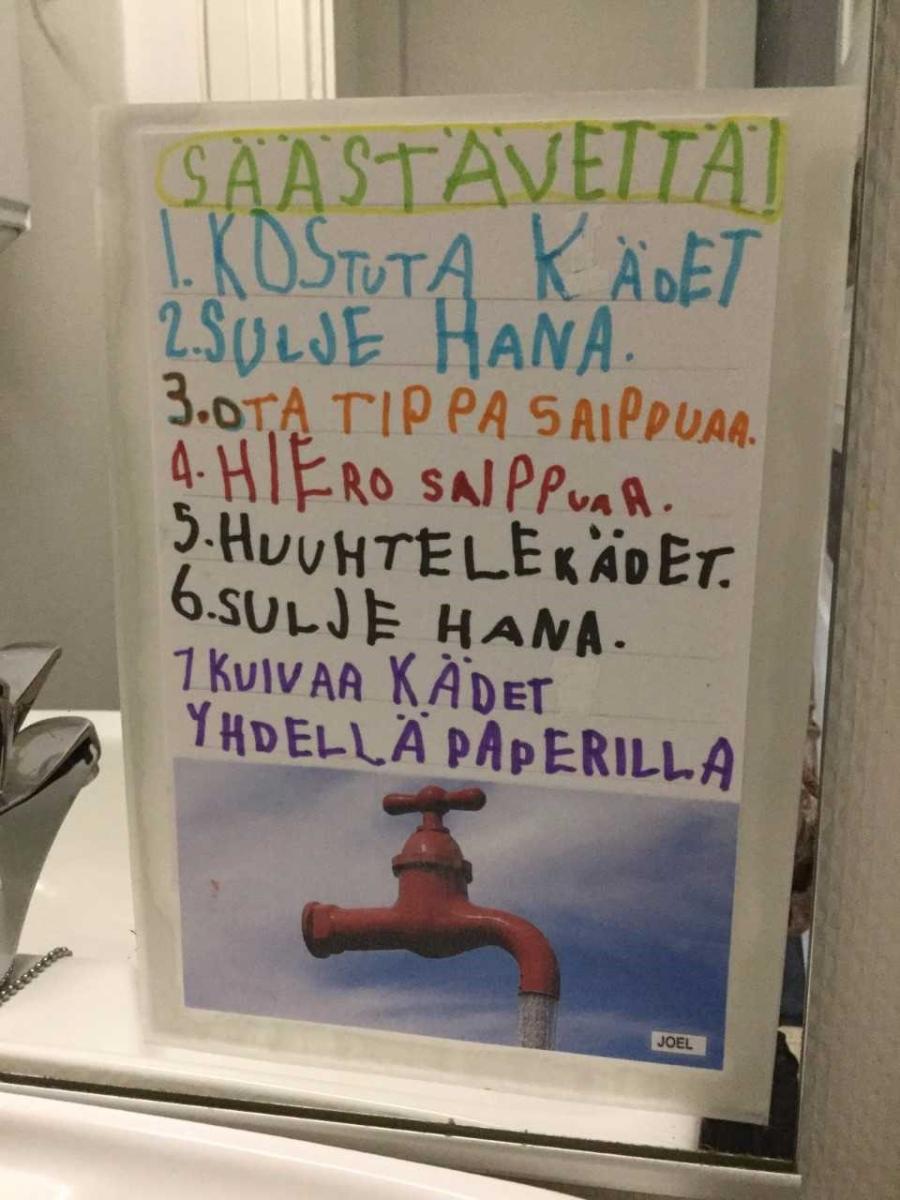 Oppilaiden käsin kirjoittama ohjeistus veden käytöstä. Säästä vettä -ohje kuuluu: 1. Kostuta kädet, 2. Sulje hana, 3. Ota tippa saippuaa, 4. Hiero saippuaa, 5, Huuhtele kädet, 6. Sulje hana, 7. Kuivaa kädet yhdellä paperilla