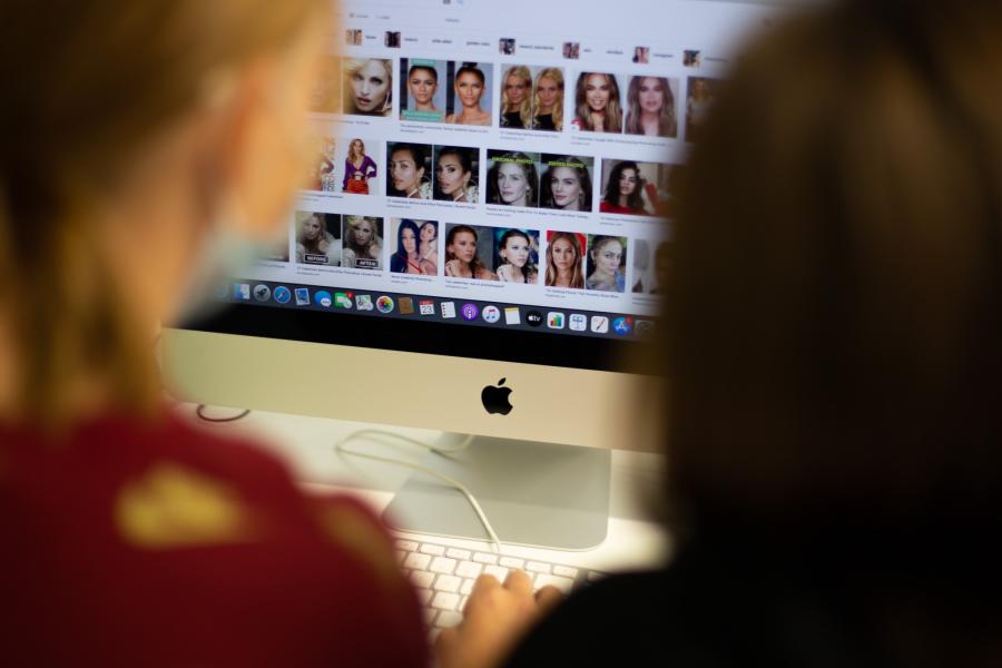 Kuvan etualalla on kahden oppilaan epätarkat selät ja he selaavat internetin kuvahakupalvelun tuloksia, jossa näkyy julkisuuden naishenkilöiden kasvomuotokuvia.