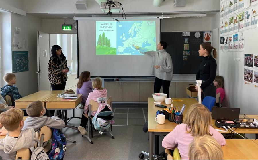 Opettaja esittelee seinälle heijastettua karttakuvaa, lapset seuraavat pulpeteissaan.