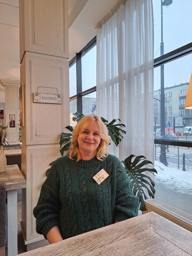 Kuvassa nainen istuu pöydän ääressä ikkunan vieressä. Ulkona näkyy lunta.