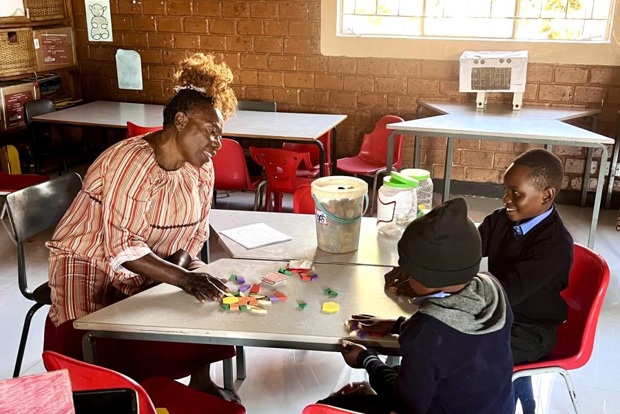 A teacher is working with two of her students in a classroom in Lusaka, Zambia.