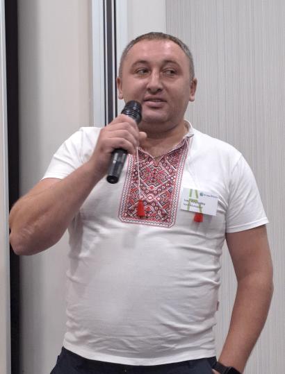 Man in a white traditional Ukrainian shirt talking to a microphone